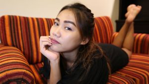 Cute Asian student poses on couch