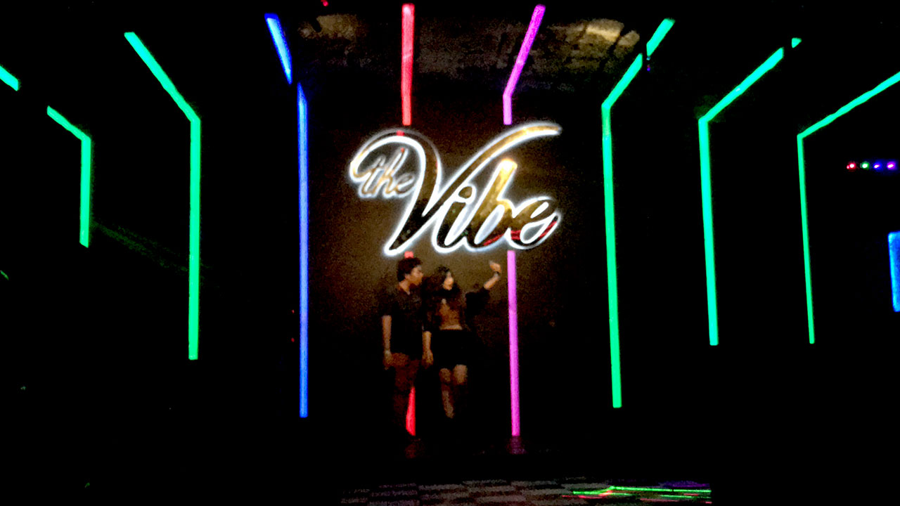 Couple takes selfie inside Vibe Disco under big The Vibe sign