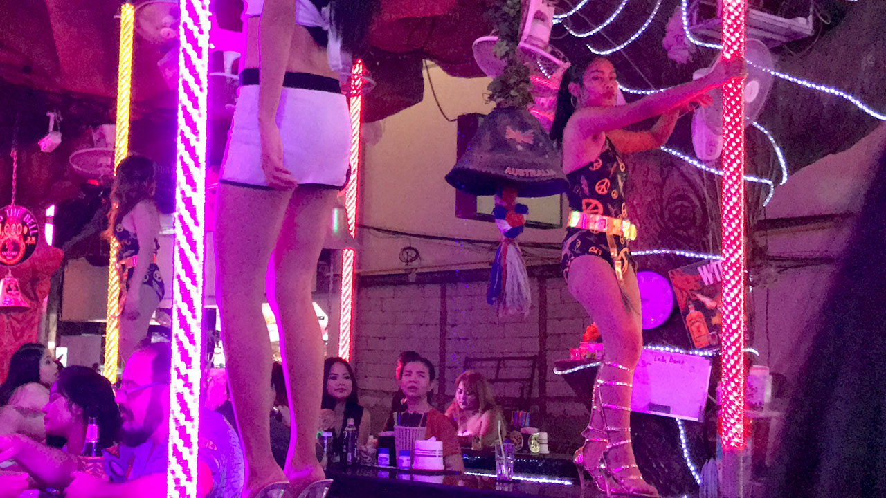 View inside establishment showing BEER BAR SLUTS dancing on stripper poles