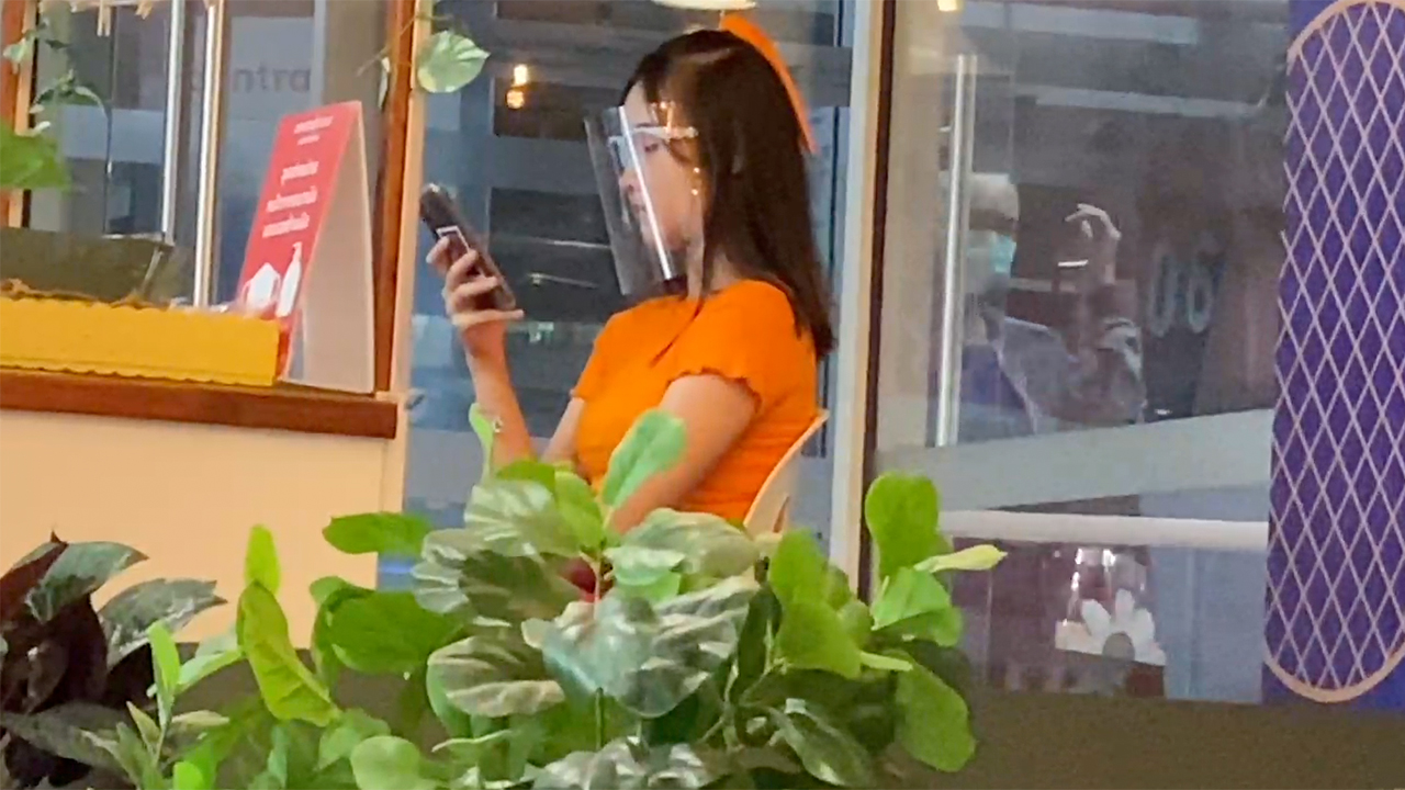Thai girl in face shield at mall using phone and tip to get Cute Girls Numbers