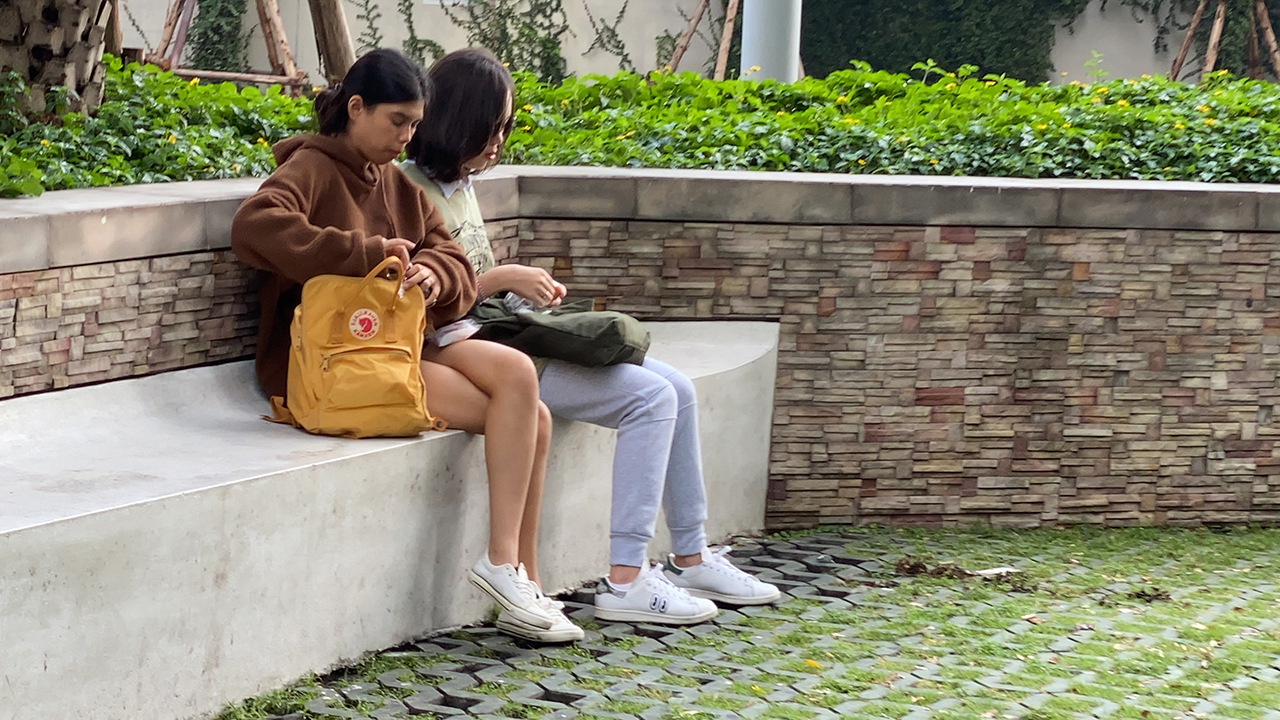 Thai girls sitting down near Empty Shopping Mall in Bangkok