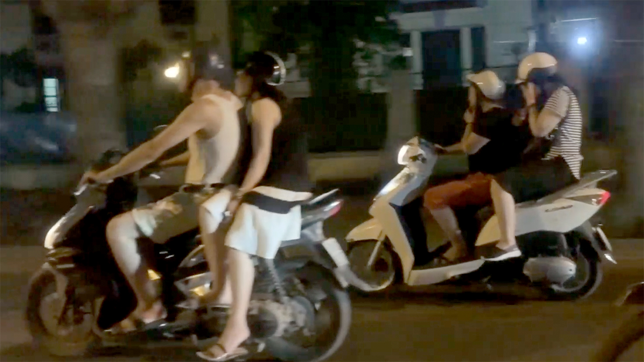 Couples riding mopeds while seen from window of Hanoi Taxi Scam trip
