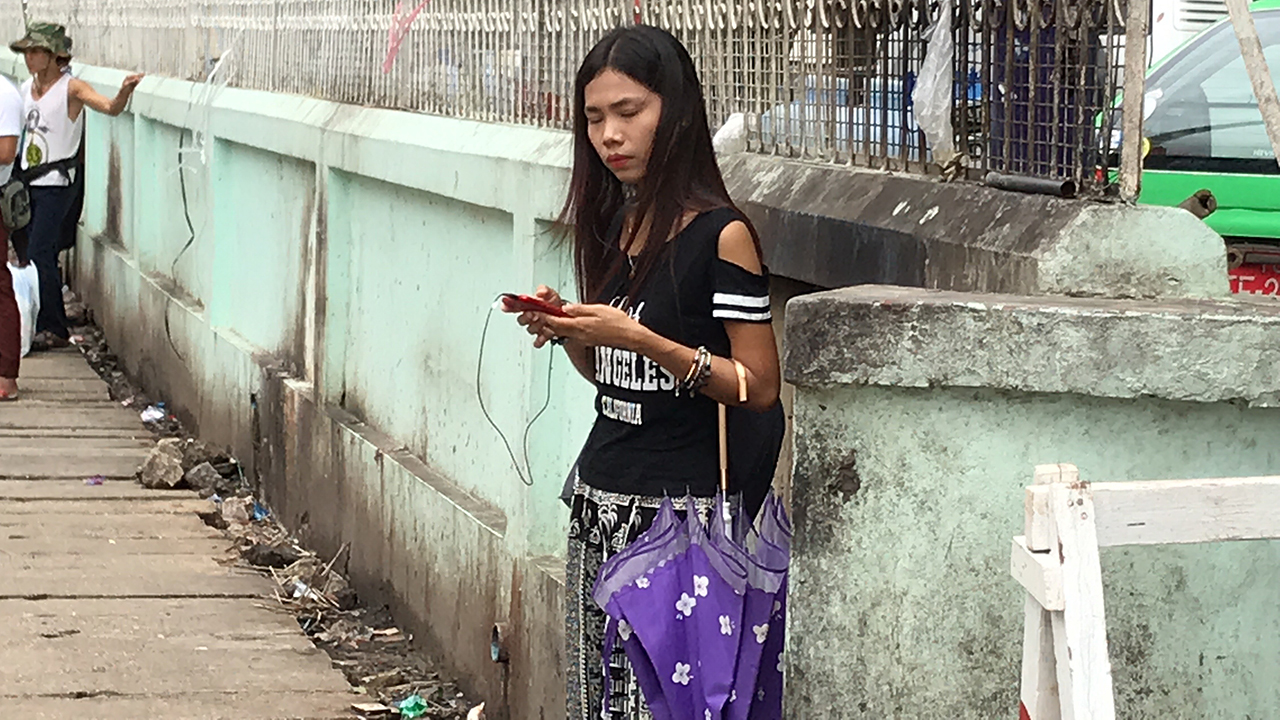Shy Burmese girl texting outside of Yuzana Plaza