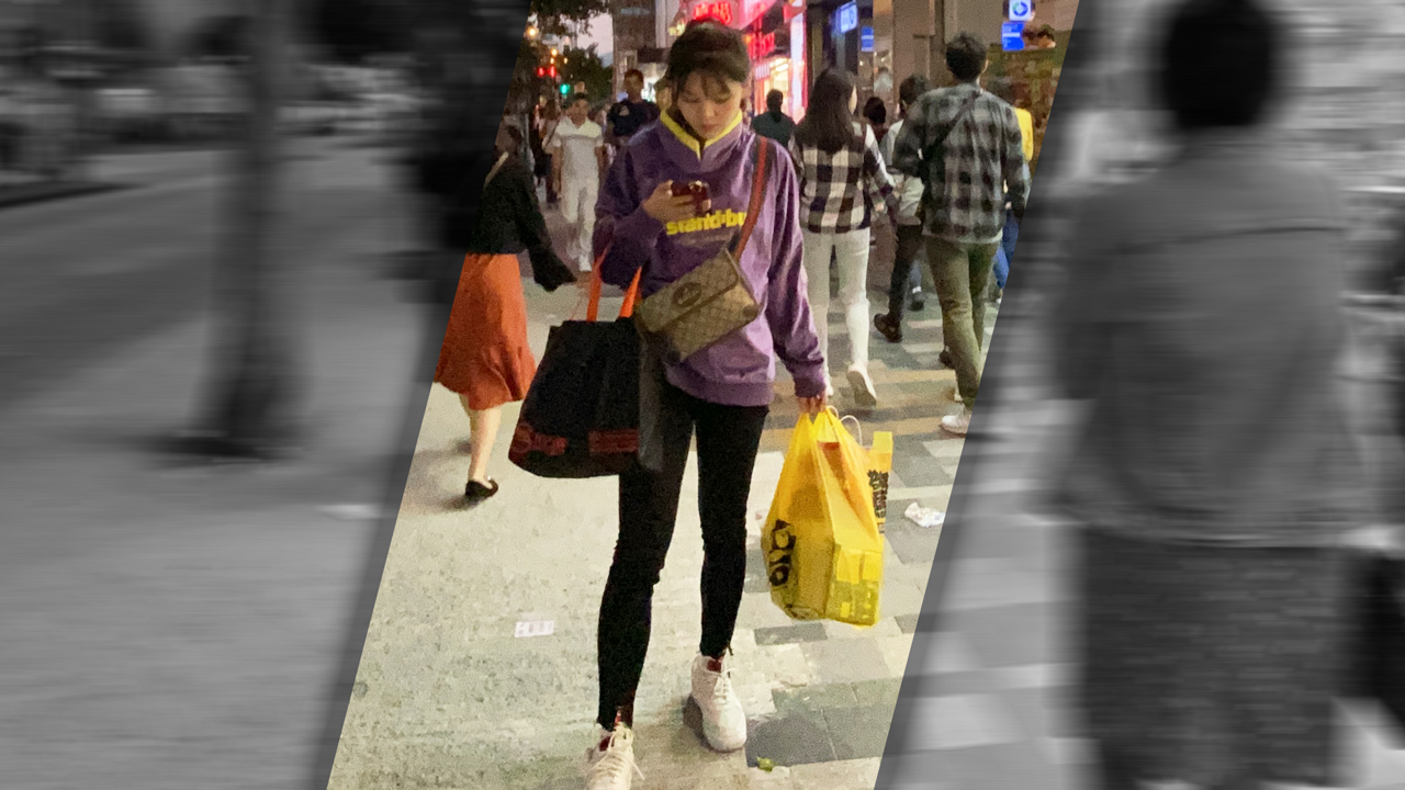 Asian Girl In Yoga Pants stands in sidewalk while texting and holding shopping bags