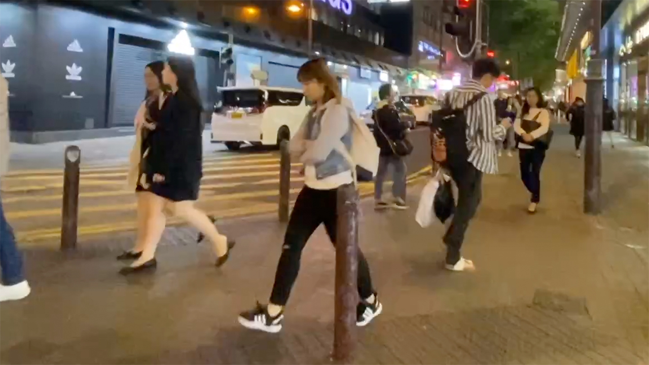 People walking along sidewalk in Hong Kong At Night