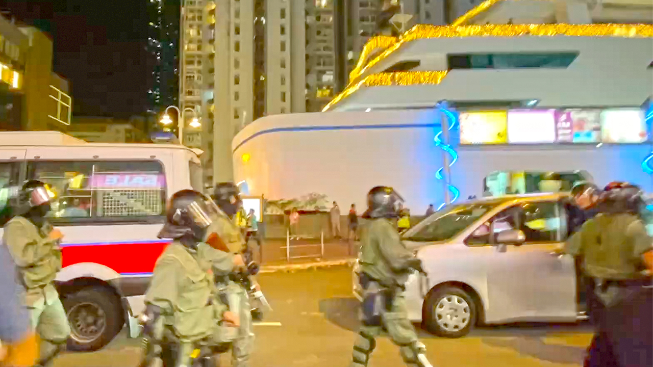 View of Hong Kong Police force walking street in riot gear at night