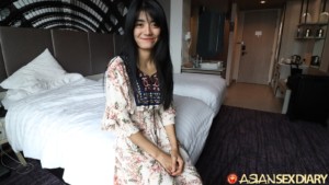 Long hair Asian teen on edge of bed