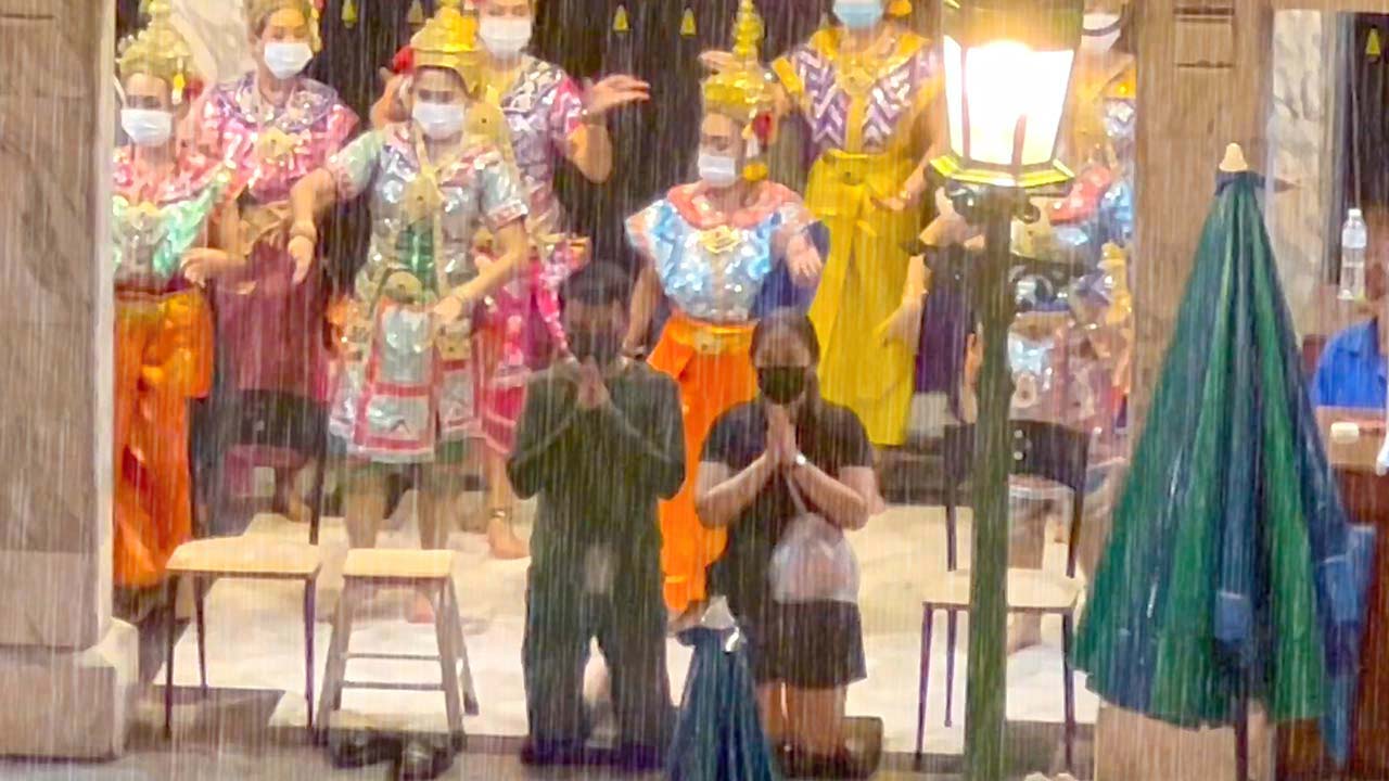 Thai couple pray at temple along street of Bangkok In The Rain