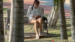 Average village girl in shorts sitting at park bench