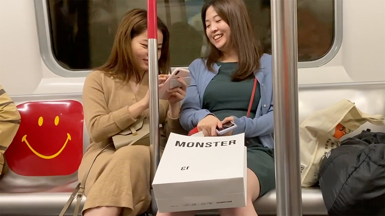 Chubby Asian Gils laughing at something on their phone on MRT