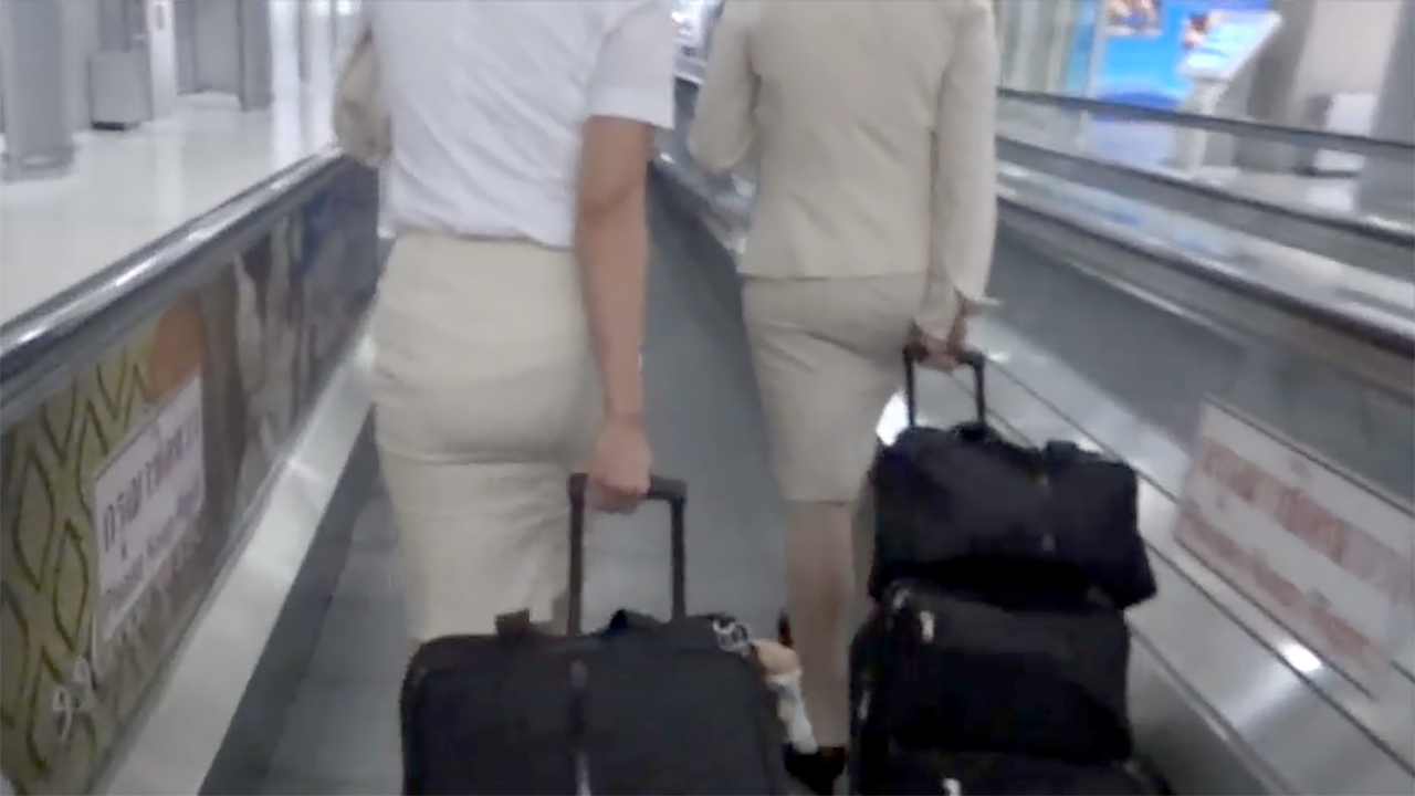 Following two FLight Attendant Skirts inside the airport pulling luggage