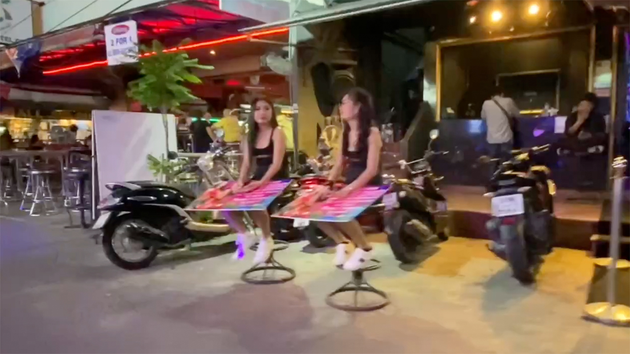 2 Pretty Asians Sitting on stools outside next to motorcycle