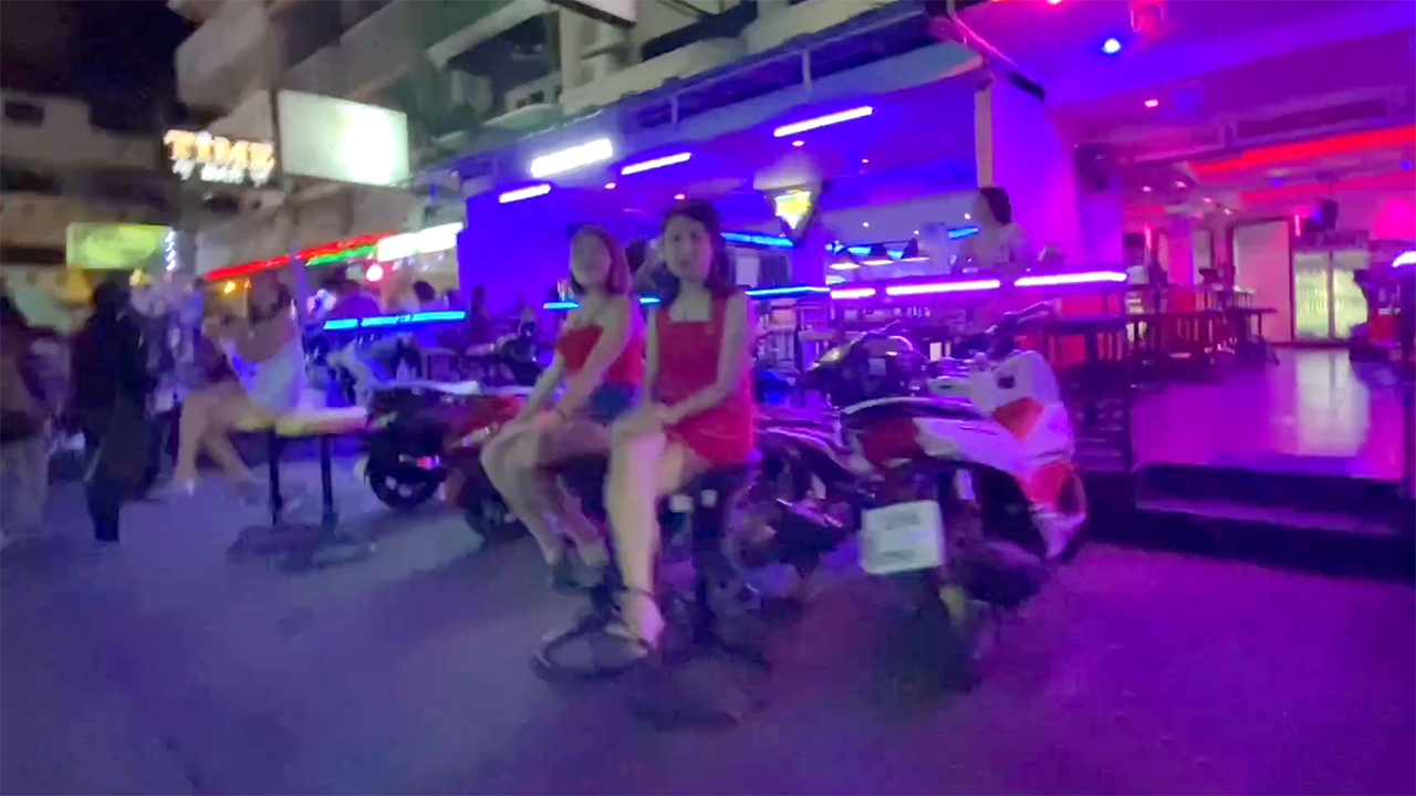 Cute Thai girls sit on stools outside a Soi LK club