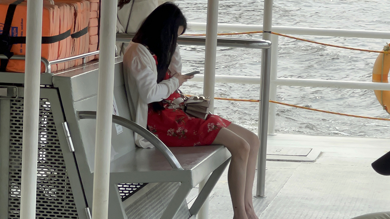 Sitting Cute Girl On Boat texting as the waves go by