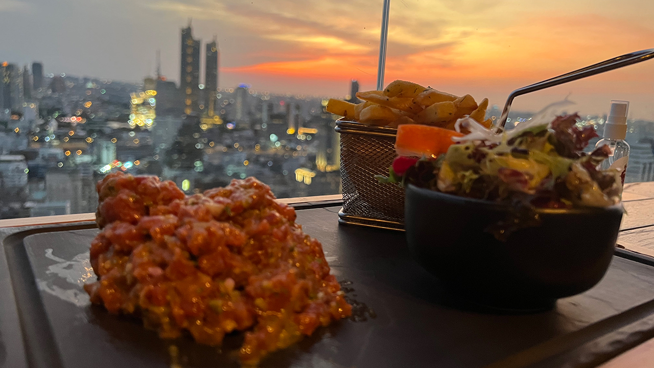 View of prepared French Steak Tartare at sunset on a Bangkok rooftop