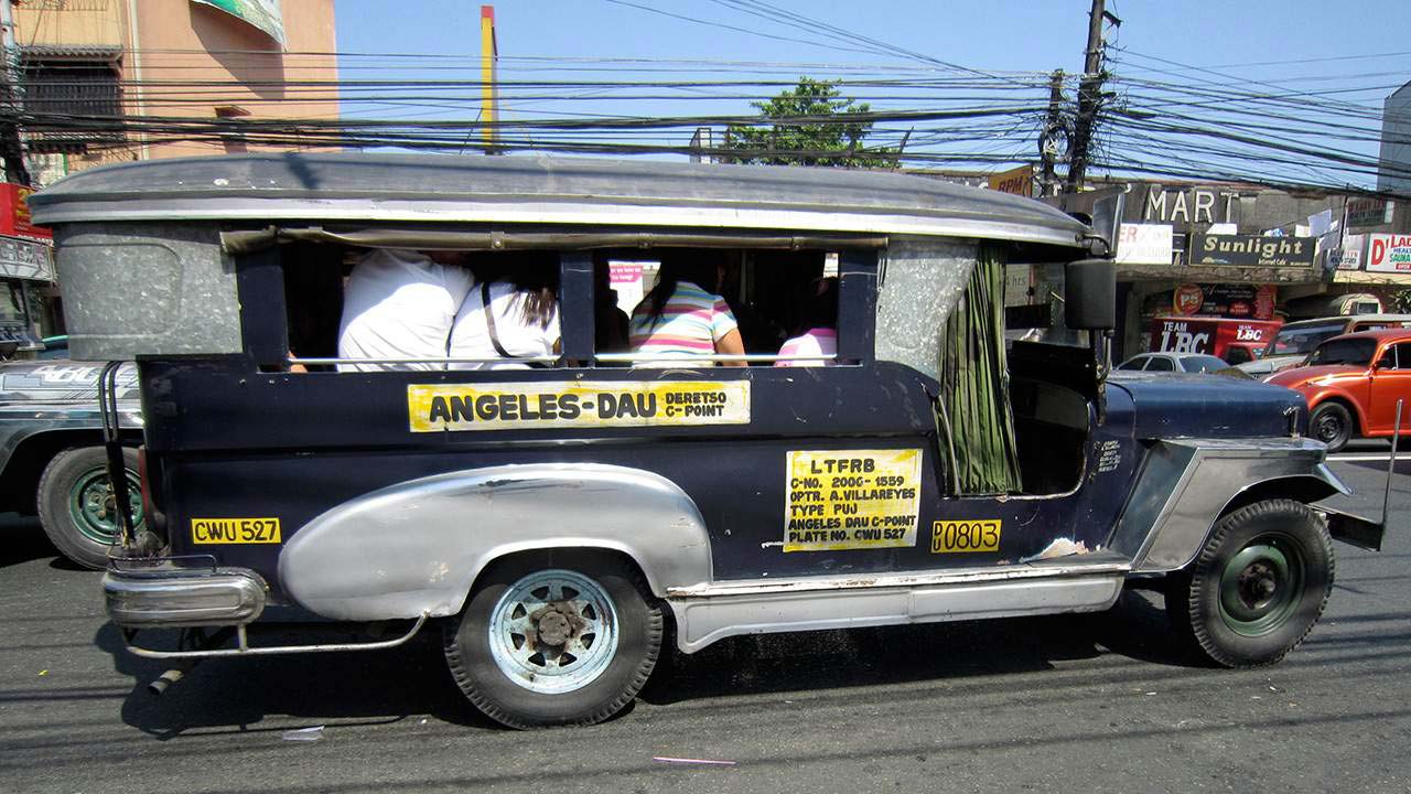 Classic Jeepney on road in ANgeles City with passengers in back